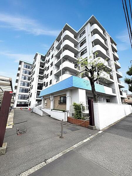 青い屋根がアクセントとなる、緑に囲まれた穏やかな低層集合住宅。