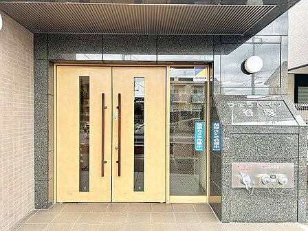重厚感のある石張りの意匠と温もりある木目が調和する落ち着いた佇まいのエントランス