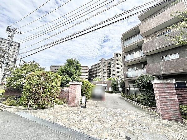 緑豊かな植栽と重厚感のある門構えが調和する、落ち着いた佇まいのアプローチ。