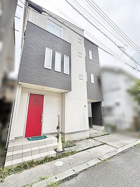 洗練されたモノトーンの外観に鮮やかな赤のドアが映えるモダンな佇まい