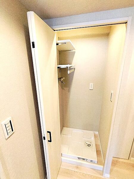 廊下に配置された洗濯機置き場は扉付。上部に棚も設けてあります。