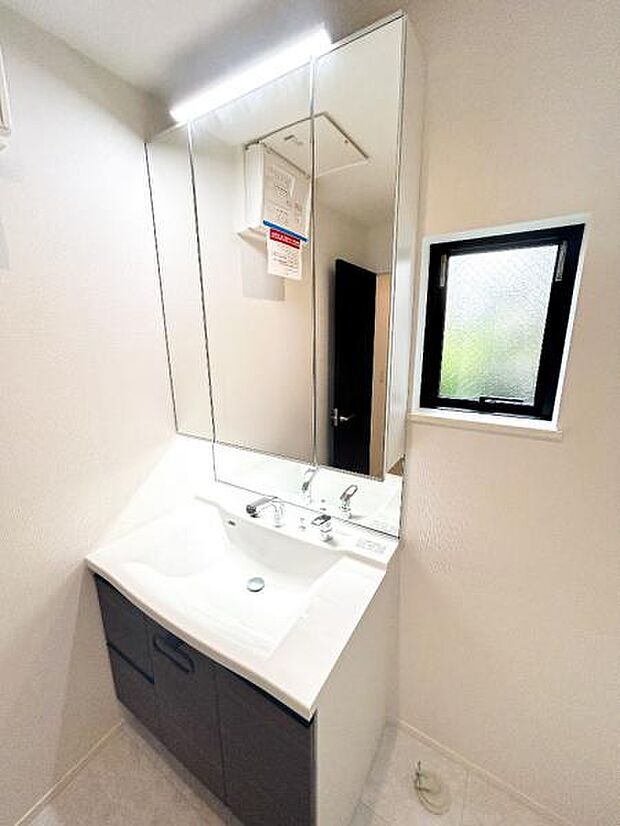 【洗面化粧台】洗面台には三面鏡を採用。下部のキャビネットの収納も容量が大きく、また鏡を開けると収納スペースがあり、散らかりやすい洗面スペースをすっきりお使いいただけます。