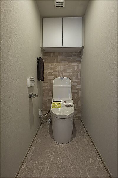 年間を通して快適に使える、温水洗浄便座付きのトイレです。上部吊戸棚があり、トイレットペーパーや掃除用品など、生活感の出やすいアイテムを隠して収納可能です。