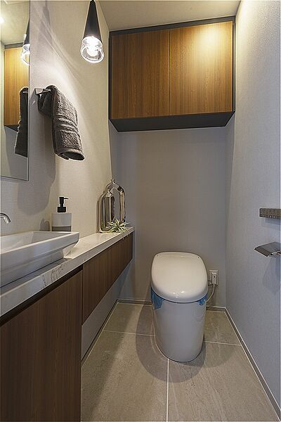 毎日清潔に使用できる温水洗浄便座付きのトイレ。壁にリモコンを備えており、操作がしやすいです。独立した手洗いと鏡を設け、ゲストも周囲を気にせず身だしなみを整えられます。