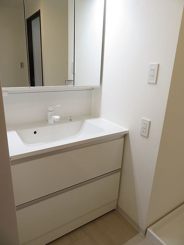 広いシンク・シャワー付きの洗面化粧台です。便利な鏡裏収納があり、清潔感のある空間を保てますね。