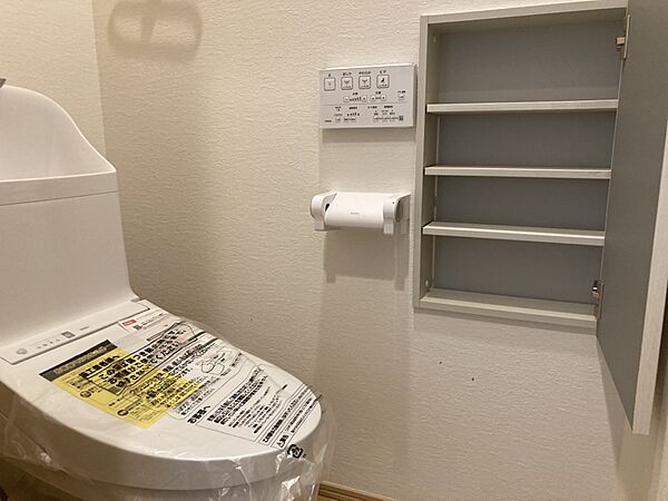 【トイレ】壁面に収納スペースが備わっており、掃除道具・トイレットペーパーなどの収納に便利です。操作リモコンが壁付けのため、スムーズに操作ができます。