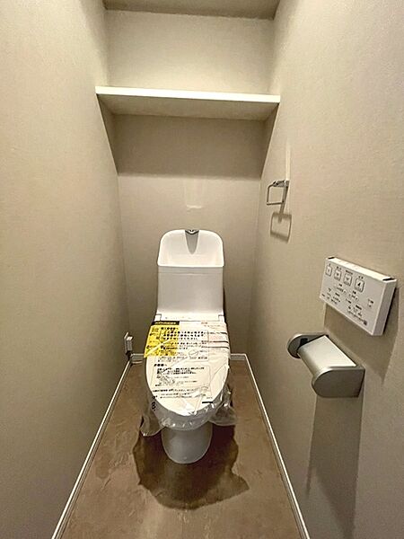 快適な温水洗浄便座を設置。上部には収納棚があり、トイレットペーパーのストックや小物整理に便利です。