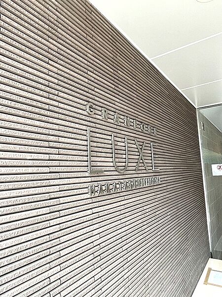 建物の顔となるエントランス。端正なタイル貼りの壁面に、クールな印象のロゴが配置されています。