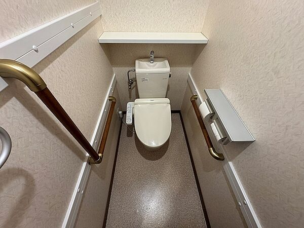 手すりが設置され、快適にご利用いただけるトイレ空間です。温水洗浄便座と上部棚で機能性も確保しています。
