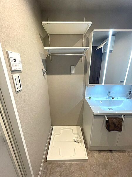 洗濯機置き場と収納棚を設けた洗面所。機能的な空間で、日々の暮らしをサポートします。洗面化粧台も備わり、身支度もスムーズに行えます。