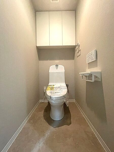 上部収納とカウンターが設置されたトイレ空間。清潔感のある落ち着いた色合いで、日々の暮らしをサポートします。
