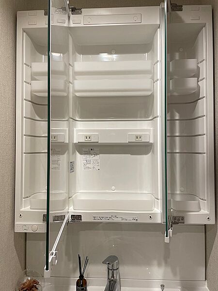 三面鏡の裏に隠された収納で、洗面台周りをすっきりと整頓できます。充電に便利なコンセントも完備。