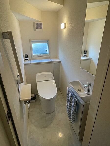 明るい採光窓と独立手洗い器を備えたトイレは、清潔感があり、居心地の良い空間です。収納棚もあり、機能性も兼ね備えています。