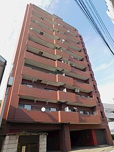 外観：開放的なバルコニーが印象的なマンション。都市の風景に溶け込む赤レンガ調の外観が魅力です。