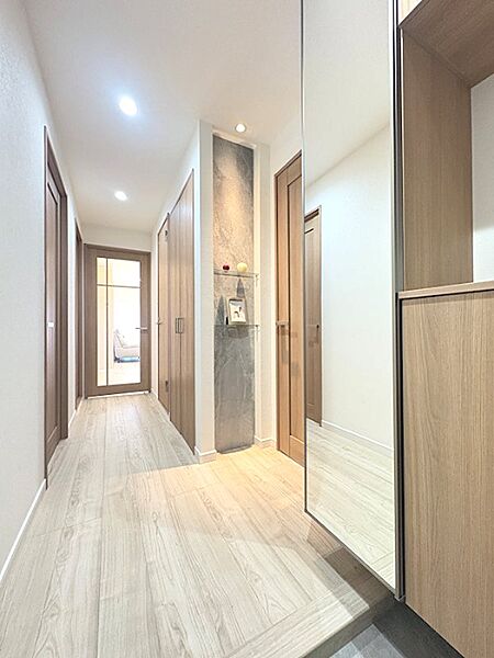 温かみのある木目調の床と建具が調和し、洗練された空間を演出。ダウンライトが心地よい明るさを添え、壁面のニッチはインテリアのアクセントに。