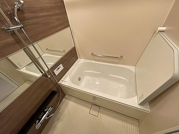 木目調の壁が落ち着いた雰囲気を醸し出す浴室です。ゆったりと体を伸ばせる浴槽で、一日の疲れを癒すバスタイムをお楽しみください。浴室乾燥機も備わり、雨の日の洗濯物も安心です。