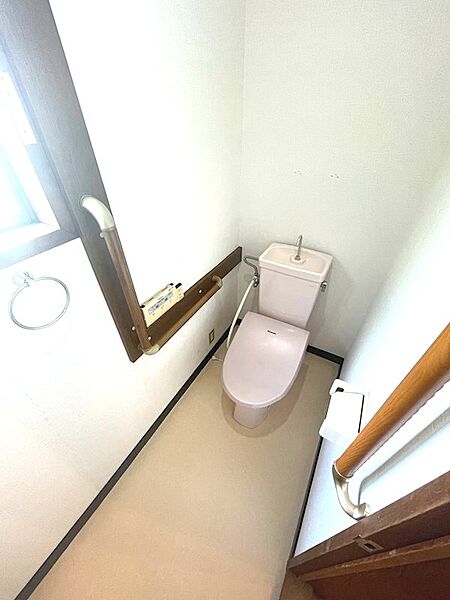 窓から自然光が差し込む明るいトイレ空間。手すり付きで、ご高齢の方も安心してお使いいただけます。
