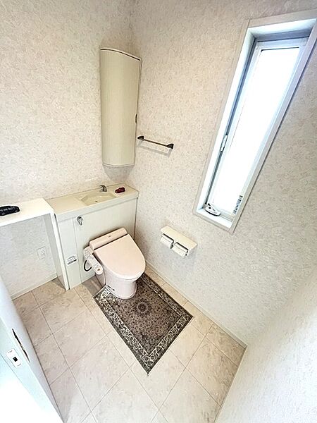 自然光を取り込む縦長窓が明るい印象のトイレ空間。手洗いカウンターや収納も備え、快適にお使いいただけます。