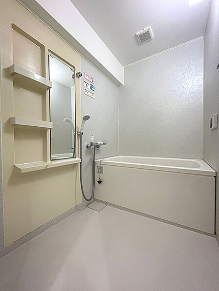 清潔感のある浴室で、一日の疲れをゆったりと癒せます。換気扇付きで湿気対策も考慮されています。棚や鏡もあり、使い勝手の良い空間です。