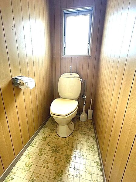 清潔感のあるトイレには、換気に役立つ窓を設置。木目調の壁と花柄の床が温かみのある空間を演出します。