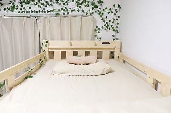 緑の装飾が壁に映えるお部屋。木製のベッドフレームが自然な温もりを感じさせ、心地よい休息を提供します。