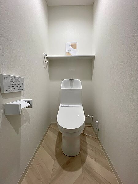 温水洗浄便座付きの快適なトイレ空間。上部の棚は収納にも便利で、空間を有効活用できます。清潔感あふれるホワイトを基調とした内装です。