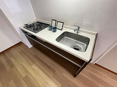 3口コンロと広々シンクを備えたキッチン。収納力のある引き出し式収納で、調理器具もすっきり片付きます。日々の料理を快適にサポートします。