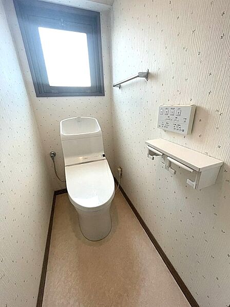 窓から自然光が差し込む、明るく清潔感のあるトイレです。温水洗浄便座や2連ホルダーなど、機能性も兼ね備えています。