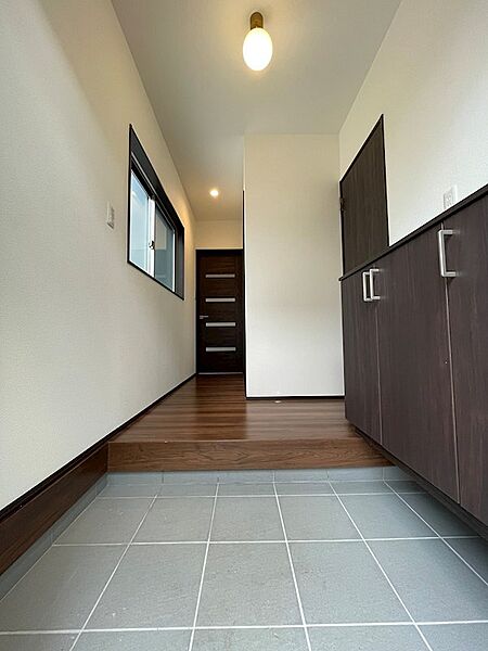玄関から続く廊下は、窓からの光と落ち着いた色合いの建具で、明るく洗練された空間を演出します。収納も充実しています。