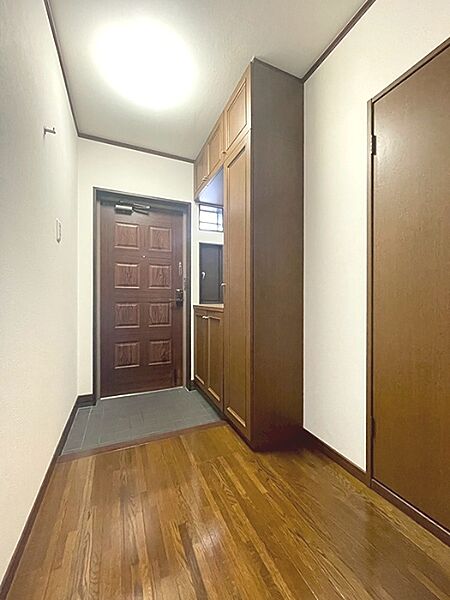 温もりを感じる木目調の玄関ドアと収納が、住まいの顔となる空間を演出します。明るい照明が心地よい雰囲気を醸し出し、帰宅を優しく迎えます。