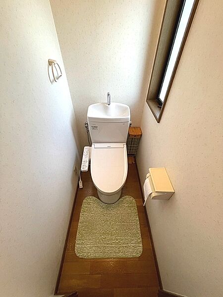 窓から自然光が差し込む、明るいトイレです。手洗い付きで清潔を保ちやすい設計です。ウォシュレット機能も備わっています。