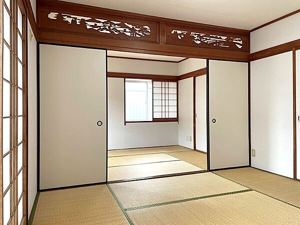 趣のある彫刻欄間が目を引く和室。障子からやわらかな光が差し込み、畳の香りが心地よい空間です。