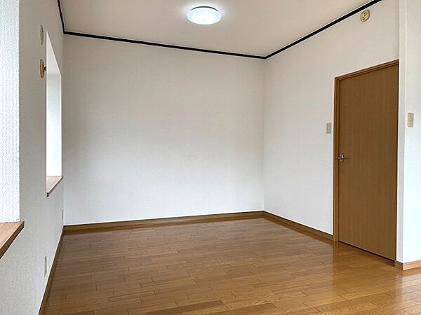 明るい木目調のフローリングが特徴的な居室。窓からは光が差し込み、柔らかな印象を与えます。新生活のスタートにぴったりの空間です。