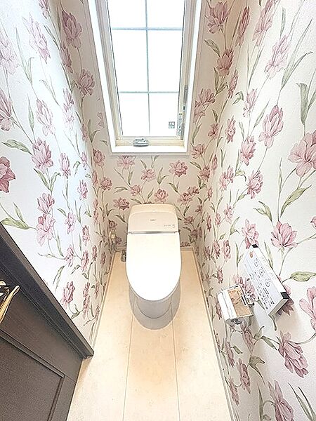 花柄のクロスが華やかなトイレ空間。窓から光が差し込み、明るく清潔感のある雰囲気です。