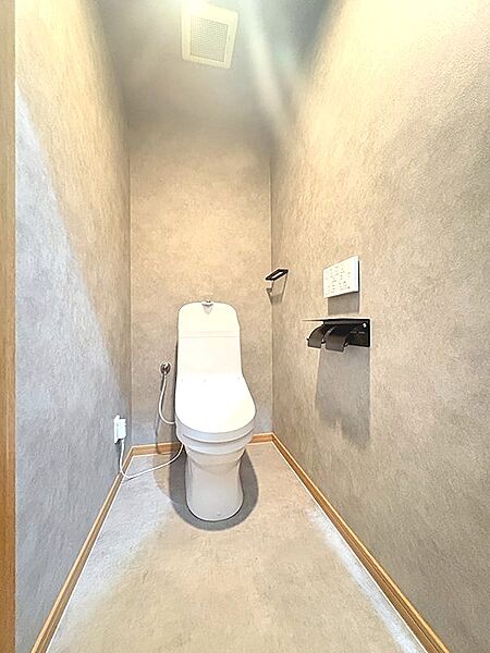 落ち着いた色合いで統一されたトイレ空間。清潔感があり、日々の暮らしに心地よさをもたらします。壁面には換気扇も設置されています。