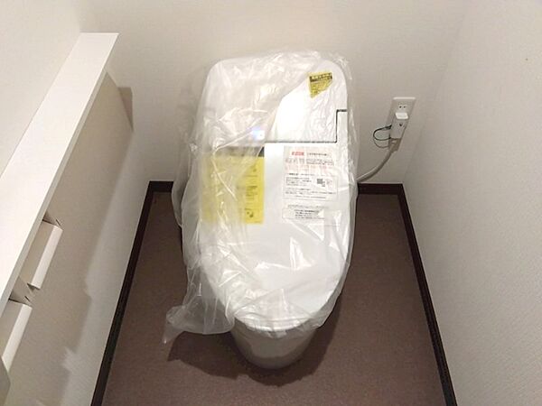 新品のトイレで清潔感あふれる空間。サイドの収納棚がすっきりとした印象を与えます。新生活を快適に始めるための設備が整っています。