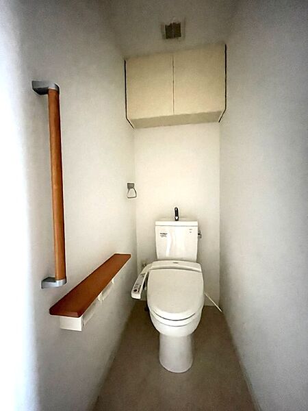 手すりやカウンター、収納棚が備え付けられた、機能的なトイレ空間です。快適さと使いやすさに配慮された設計です。