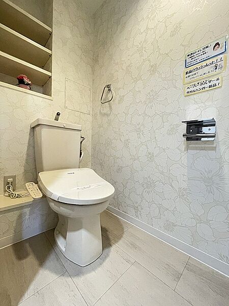 清潔感あふれるトイレは、訪れるたびに気分をリフレッシュさせてくれます。花柄の壁紙が空間に彩りを添え、穏やかな時間を提供します。収納棚も完備しており、機能性も兼ね備えています。