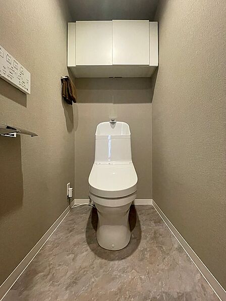 清潔感のある温水洗浄便座を設置。上部には吊戸棚があり、トイレットペーパーなどの収納に便利です。日々の暮らしを快適にする空間です。