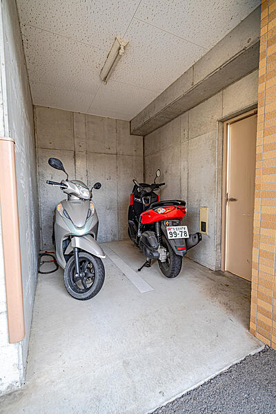 大切な愛車を雨や風から守る、コンクリート壁に囲まれた屋根付きのバイク置き場。