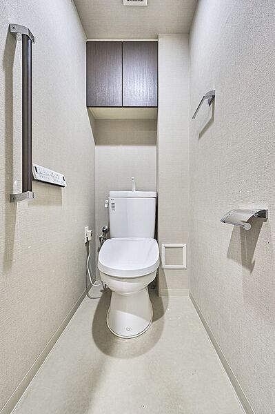 吊戸棚を備えた機能的なトイレ。トイレットペーパーや日用品をすっきり収納できます。