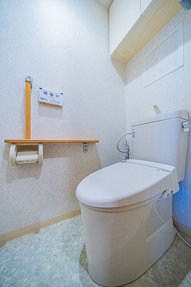 手すりや上部に吊戸棚が設置されているトイレになります。