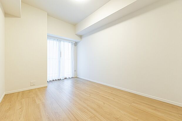 壁紙、床材ともに明るい色合いで統一されているので、広く感じられる洋室