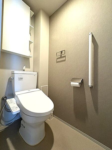 トイレの様子です。小物類の収納に重宝する吊戸棚も付いています。