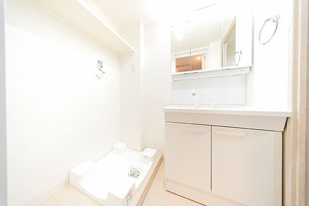 三面鏡キャビネットを備えた洗面化粧台と洗濯機置場が配置された洗面室。スッキリとした空間で身支度をすることができます。