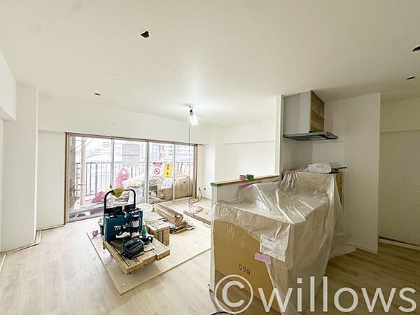 現在リノベーション施工中のお部屋です。バルコニーからの光が入る約15.7帖のLDKは、対面キッチンを備えた解放感ある造りです。資材が入っておりますが、広さや日当たりの確認にご活用ください。
