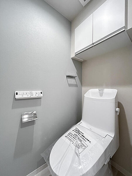 お掃除道具やトイレットペーパーの収納に適した吊り戸棚を採用したトイレ。