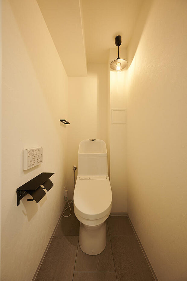 【トイレ】手洗い付きのトイレですぐ手を洗って拭けるのが良いですね。トイレットペーパーホルダーとタオルホルダーは、黒で統一してかっこいい感じです。照明が壁に反射するのが良いですね。温水洗浄暖房便座あり