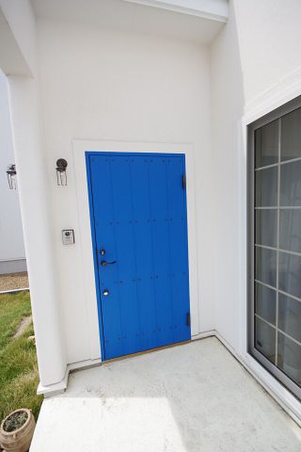 白い塗り壁に青いドアが眩しい玄関