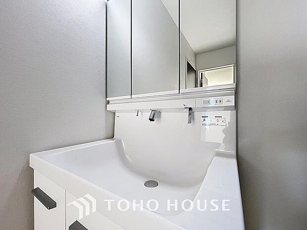 「清潔な印象の洗面室」明るく清潔感のある色調で纏められた洗面室は、機能性に富んだ三面鏡と使い勝手の良い収納を完備した洗面台を設置。洗濯機置場も完備し、大変充実しております。